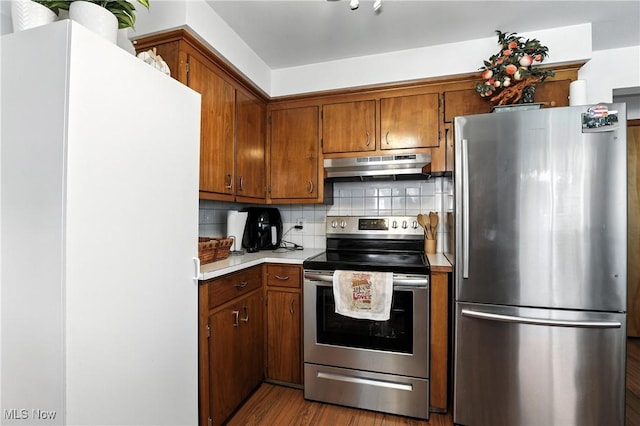 1932 Meister Rd, Lorain, OH 44053 - kitchen with stainless steel appliances, under cabinet range hood, backsplash, brown cabinetry, and light countertops