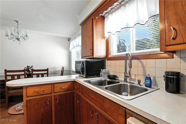 1932 Meister Rd, Lorain, OH 44053 - kitchen featuring light countertops, a peninsula, a chandelier, backsplash, and brown cabinets