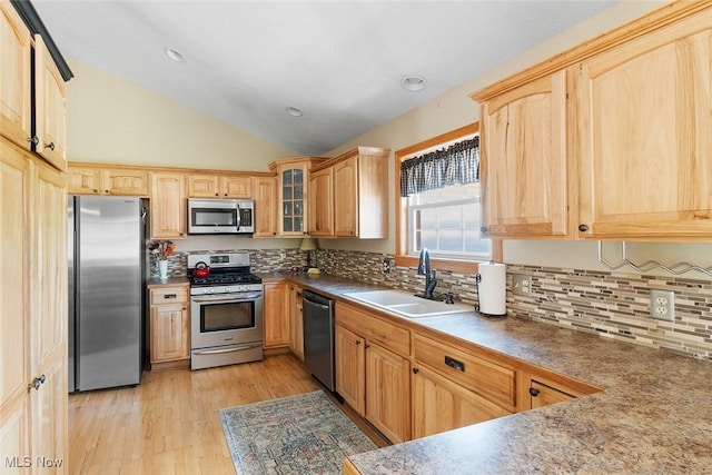 4568 Woodstone Ave NW, Massillon, OH 44647 - kitchen with appliances with stainless steel finishes, vaulted ceiling, light wood-style floors, decorative backsplash, and glass insert cabinets