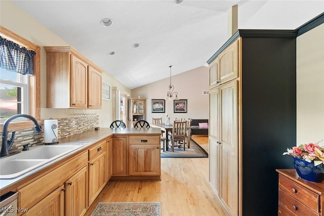 4568 Woodstone Ave NW, Massillon, OH 44647 - kitchen featuring light wood-type flooring, lofted ceiling, a peninsula, a chandelier, and backsplash