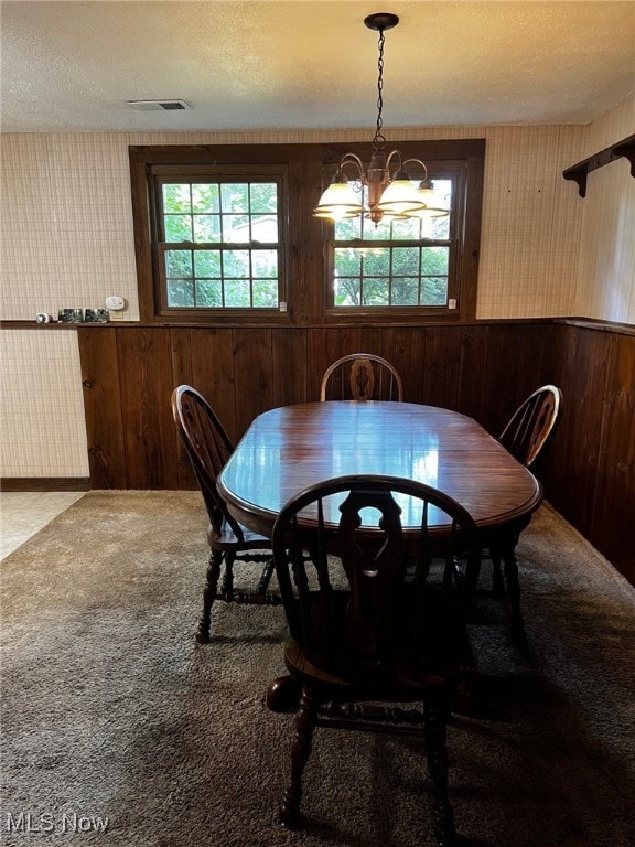 8001 Cherry Hl, Warren, OH 44484 - dining space featuring wood walls, a chandelier, a textured ceiling, and carpet