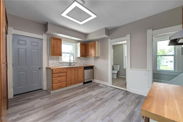 18104 Garden Blvd, Warrensville Heights, OH 44128 - kitchen with dishwasher, light countertops, light wood finished floors, brown cabinets, and decorative backsplash