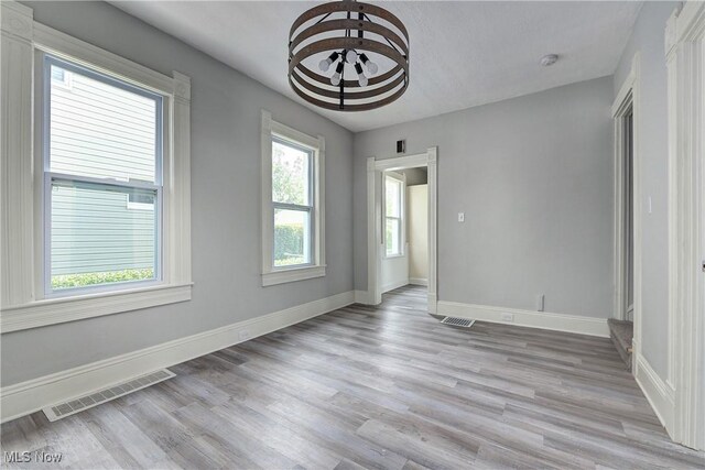 18104 Garden Blvd, Warrensville Heights, OH 44128 - empty room with light wood-style floors, a smoke detector, and a chandelier