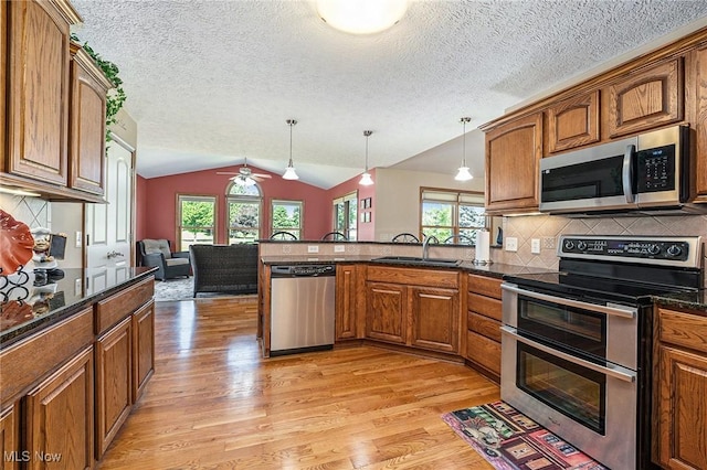 6782 Fawndale Dr, Medina, OH 44256 - kitchen featuring stainless steel appliances, a peninsula, brown cabinets, light wood-style flooring, and vaulted ceiling