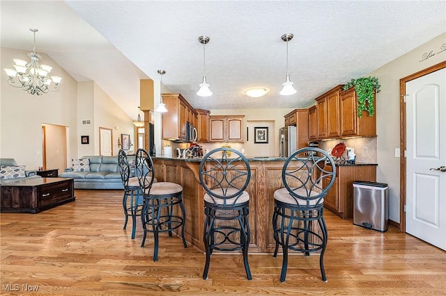 6782 Fawndale Dr, Medina, OH 44256 - kitchen with stainless steel appliances, light wood-style floors, a peninsula, a kitchen breakfast bar, and lofted ceiling