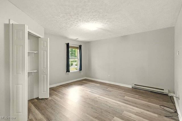 232 Damon Dr, Munroe Falls, OH 44262 - unfurnished bedroom with baseboard heating, a textured ceiling, wood finished floors, and a closet