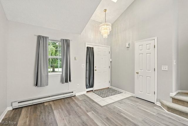232 Damon Dr, Munroe Falls, OH 44262 - entrance foyer with a baseboard radiator, a chandelier, high vaulted ceiling, wood finished floors, and stairway