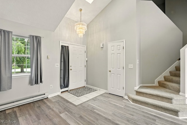 232 Damon Dr, Munroe Falls, OH 44262 - foyer entrance with high vaulted ceiling, stairs, a baseboard heating unit, wood finished floors, and a chandelier