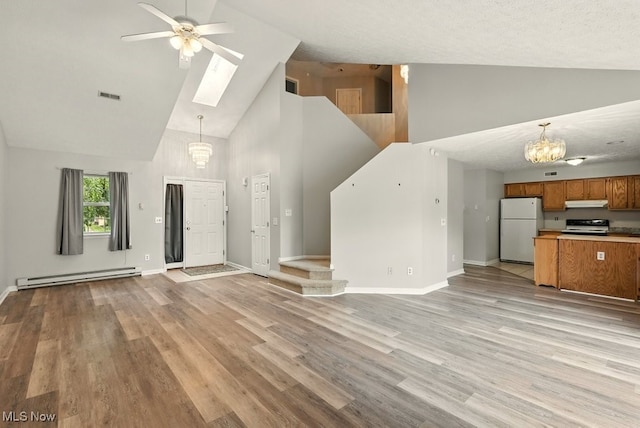 232 Damon Dr, Munroe Falls, OH 44262 - unfurnished living room featuring high vaulted ceiling, a baseboard heating unit, a chandelier, a skylight, and a ceiling fan