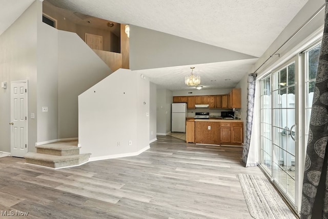 232 Damon Dr, Munroe Falls, OH 44262 - kitchen featuring freestanding refrigerator, open floor plan, brown cabinetry, high vaulted ceiling, and under cabinet range hood