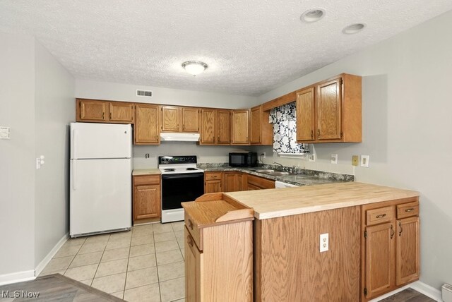232 Damon Dr, Munroe Falls, OH 44262 - kitchen with white appliances, under cabinet range hood, brown cabinetry, a peninsula, and a textured ceiling