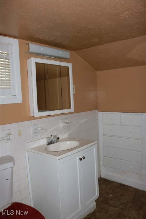 299 E 197th St, Euclid, OH 44119 - bathroom featuring vanity, tile walls, wainscoting, and vaulted ceiling