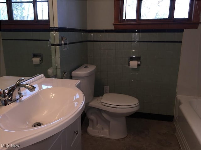 5785 Fitch Rd, North Olmsted, OH 44070 - bathroom with tile walls, a bathtub, vanity, and wainscoting