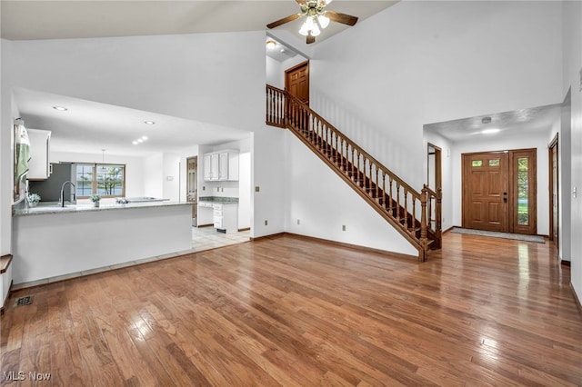 3578 County Line Rd, Madison, OH 44057 - unfurnished living room featuring a high ceiling, stairs, light wood finished floors, and a ceiling fan