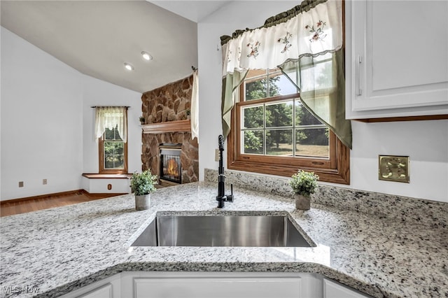 3578 County Line Rd, Madison, OH 44057 - kitchen with a fireplace, light stone counters, white cabinetry, healthy amount of natural light, and vaulted ceiling
