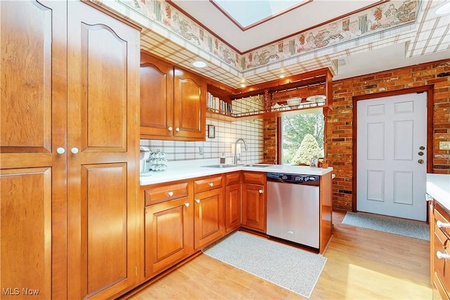 6803 County Road 22a, Bloomingdale, OH 43910 - kitchen featuring stainless steel dishwasher, light wood-style floors, light countertops, brown cabinetry, and brick wall