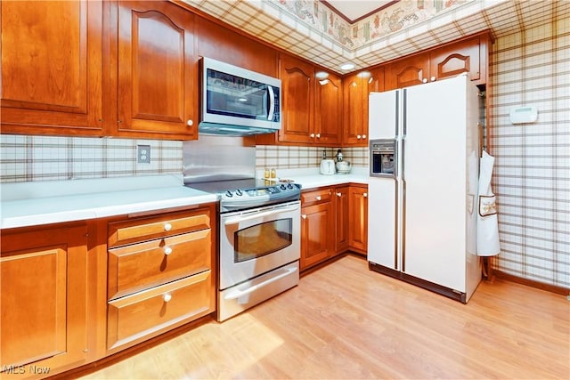 6803 County Road 22a, Bloomingdale, OH 43910 - kitchen with stainless steel appliances, wallpapered walls, light wood-type flooring, light countertops, and brown cabinetry