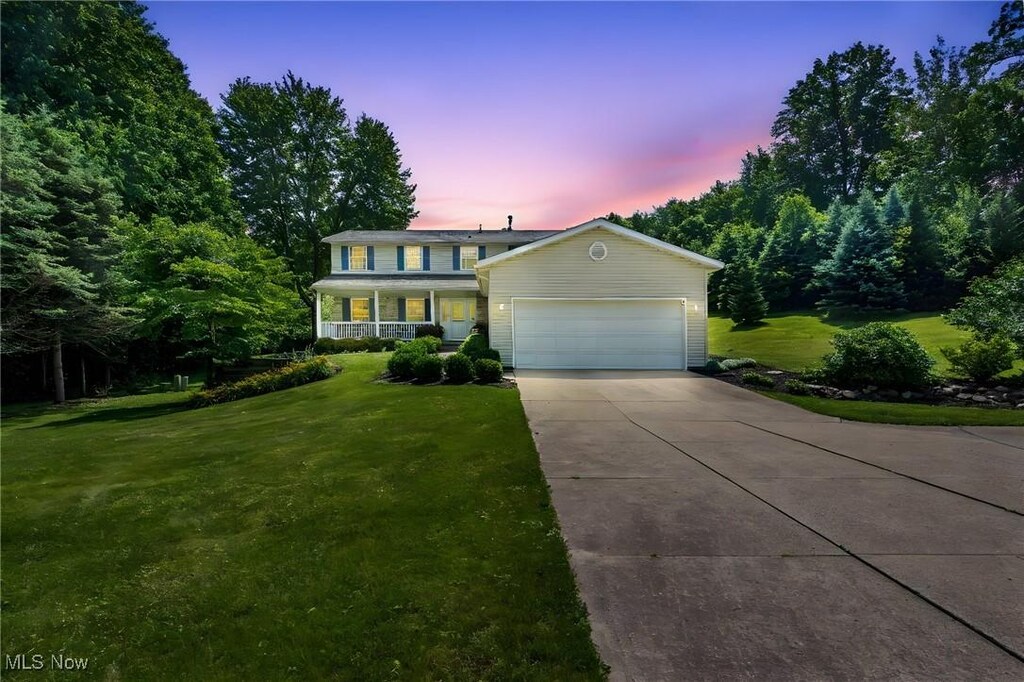 7700 Stonewood Dr NW, North Canton, OH 44720 - traditional home featuring an attached garage, a lawn, driveway, and a porch
