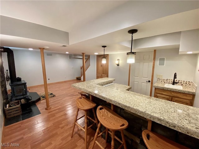 13781 Rustic Dr, North Royalton, OH 44133 - kitchen featuring light wood-type flooring, a kitchen bar, light stone counters, and pendant lighting