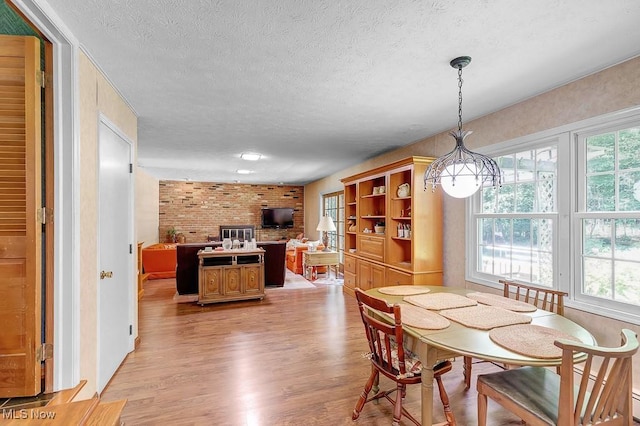 9502 Winchester Vly, Chesterland, OH 44026 - dining area featuring a textured ceiling, light wood-style floors, and brick wall