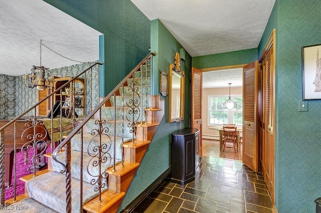 9502 Winchester Vly, Chesterland, OH 44026 - stairway featuring a chandelier, a textured ceiling, wallpapered walls, and stone tile flooring