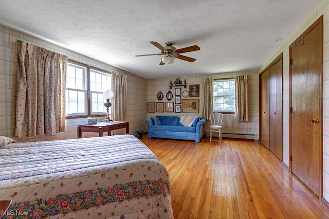 9502 Winchester Vly, Chesterland, OH 44026 - bedroom featuring baseboard heating, light wood-type flooring, wallpapered walls, a textured ceiling, and a ceiling fan