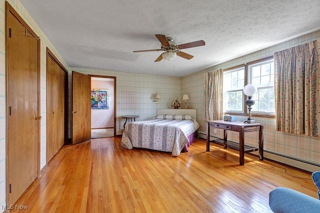 9502 Winchester Vly, Chesterland, OH 44026 - bedroom with light wood-style floors, a textured ceiling, wallpapered walls, and a baseboard heating unit
