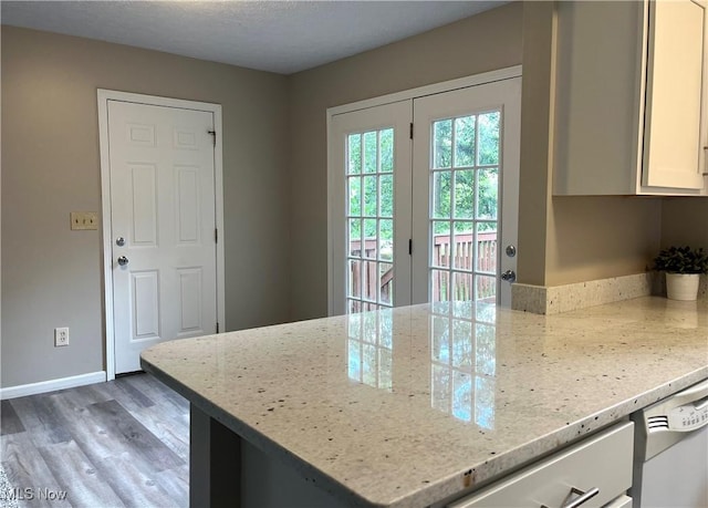 8602 Wedgewood Ave NW, North Canton, OH 44720 - kitchen with light wood-type flooring, white cabinetry, a peninsula, and light stone counters