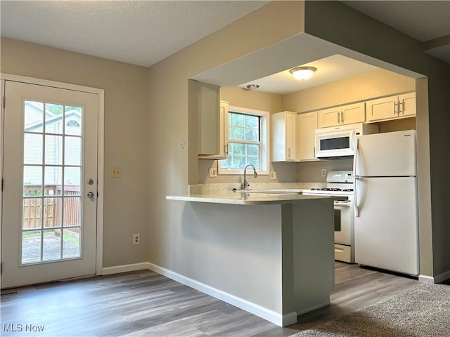 8602 Wedgewood Ave NW, North Canton, OH 44720 - kitchen with white appliances, light wood-style floors, a peninsula, light countertops, and white cabinetry