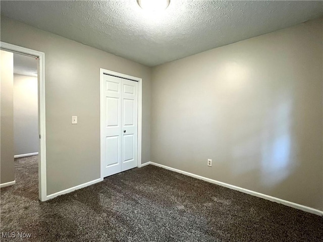 8602 Wedgewood Ave NW, North Canton, OH 44720 - unfurnished bedroom featuring dark colored carpet, a closet, and a textured ceiling