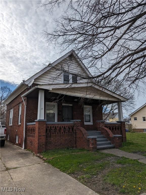 1268 E 169th St, Cleveland, OH 44110 - view of front of home featuring covered porch, brick siding, and driveway
