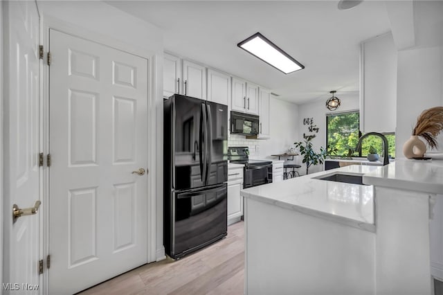 3800 Rosemont Blvd Unit 114C, Akron, OH 44333 - kitchen featuring black appliances, white cabinetry, a peninsula, backsplash, and light wood-style flooring
