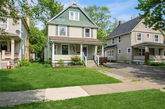 1206 Middle Ave, Elyria, OH 44035 - view of front facade featuring covered porch, a front lawn, and asphalt driveway