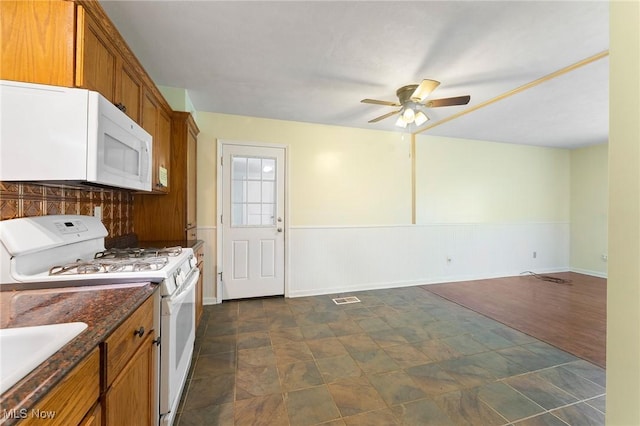293 W 14th St, Salem, OH 44460 - kitchen with white appliances, ceiling fan, stone finish flooring, brown cabinetry, and a wainscoted wall