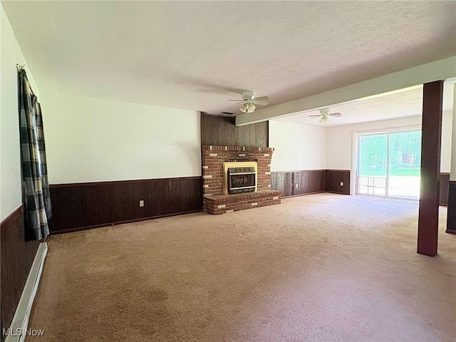 10511 Darrow Rd, Vermilion, OH 44089 - unfurnished living room featuring wainscoting, a ceiling fan, carpet, wooden walls, and a fireplace