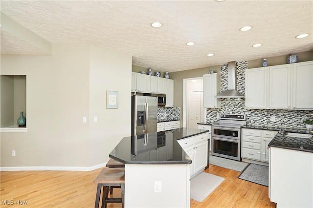 933 Alder Run Way, Akron, OH 44333 - kitchen with stainless steel appliances, wall chimney exhaust hood, a kitchen island, light wood-type flooring, and dark countertops