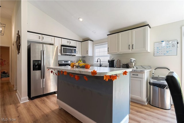 3316 Wadsworth Rd, Norton, OH 44203 - kitchen featuring appliances with stainless steel finishes, lofted ceiling, light wood-style flooring, a center island, and white cabinets