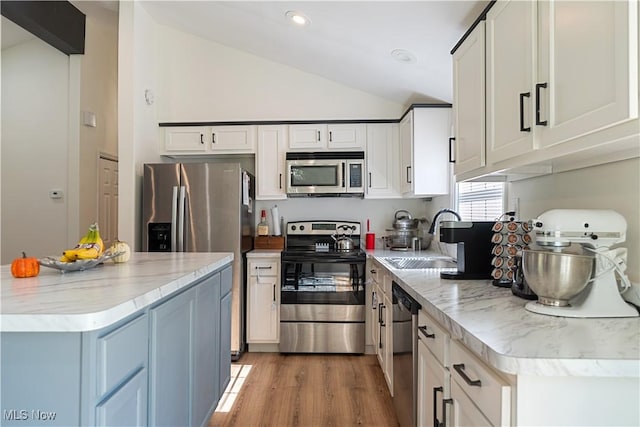 3316 Wadsworth Rd, Norton, OH 44203 - kitchen featuring stainless steel appliances, vaulted ceiling, white cabinets, light wood-style flooring, and light stone counters