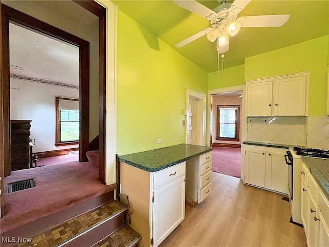 1307 W Ave, Elyria, OH 44035 - kitchen with white gas stove, white cabinetry, light wood finished floors, a ceiling fan, and tasteful backsplash