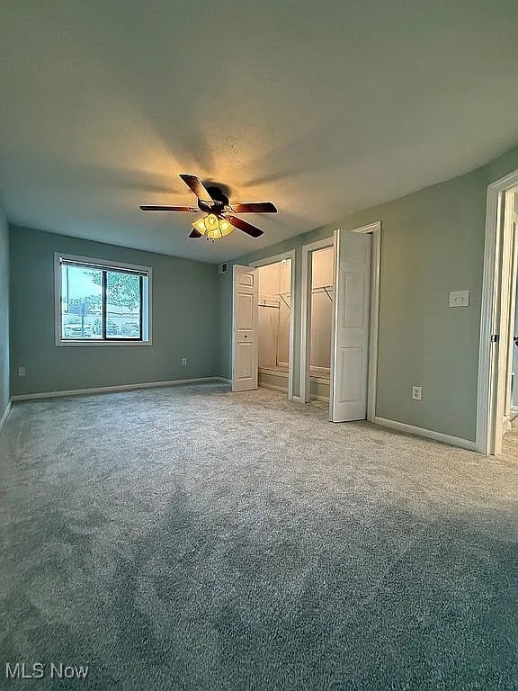 9630 Cove Dr Unit A14, North Royalton, OH 44133 - unfurnished bedroom featuring light carpet, two closets, and a ceiling fan