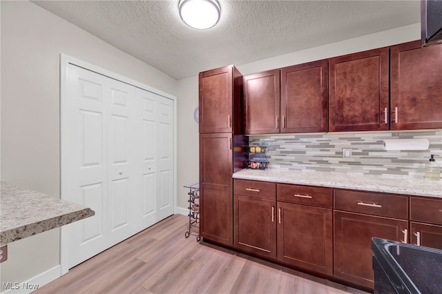 2910 N Bay Dr Unit L11, Westlake, OH 44145 - kitchen featuring light wood-style floors, decorative backsplash, a textured ceiling, and light stone counters