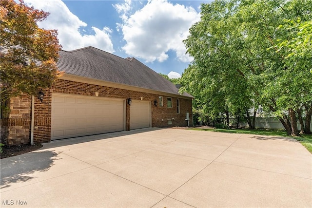 2840 Barclay Cir NW, North Canton, OH 44720 - view of side of property with brick siding, concrete driveway, a garage, and roof with shingles