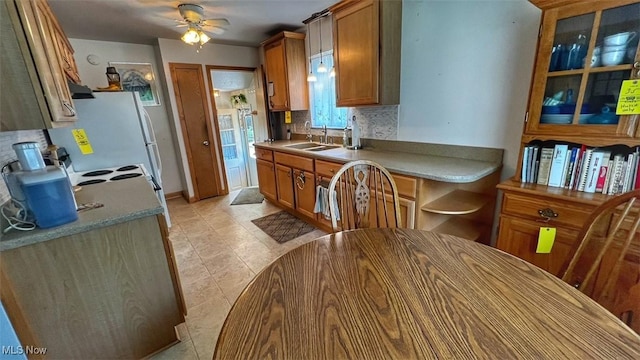 237 Kraft St, Berea, OH 44017 - kitchen featuring decorative backsplash, a ceiling fan, brown cabinets, glass insert cabinets, and under cabinet range hood