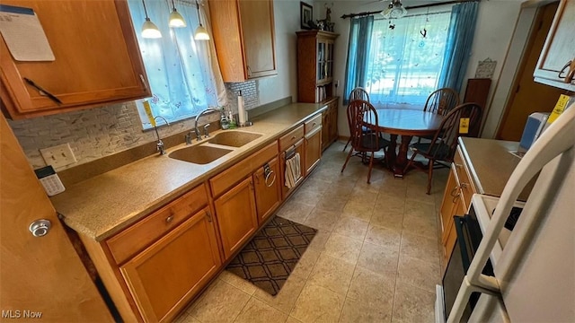 237 Kraft St, Berea, OH 44017 - kitchen with brown cabinets, healthy amount of natural light, backsplash, and decorative light fixtures