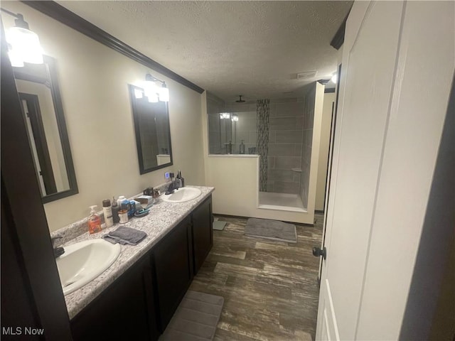 83478 Monzula Rd, Cadiz, OH 43907 - bathroom featuring a textured ceiling, double vanity, a stall shower, wood finished floors, and ornamental molding