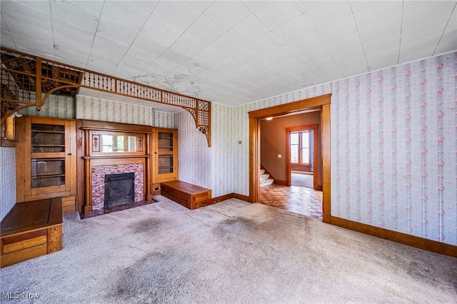 13778 Spring St, Burton, OH 44021 - unfurnished living room with wallpapered walls, carpet flooring, healthy amount of natural light, a fireplace, and stairs