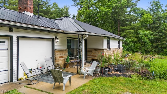 8902 Taylor May Rd, Chagrin Falls, OH 44023 - rear view of house with a metal roof, stone siding, a chimney, and a garage
