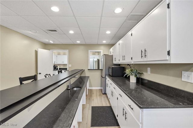 2021 King James Pkwy Unit 228, Westlake, OH 44145 - kitchen with white cabinets, light wood-style flooring, dark stone counters, recessed lighting, and stainless steel microwave