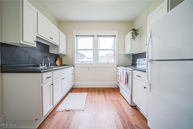 3006 6th St SW, Canton, OH 44710 - kitchen featuring white appliances, dark countertops, white cabinets, light wood-style floors, and decorative backsplash