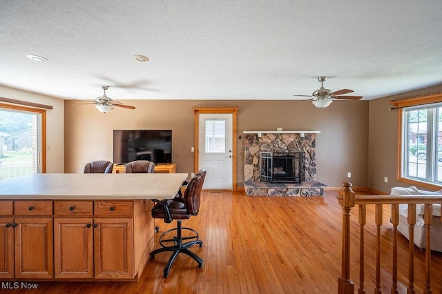 1565 Lois St, Belpre, OH 45714 - living area featuring ceiling fan, a stone fireplace, light wood finished floors, and a textured ceiling